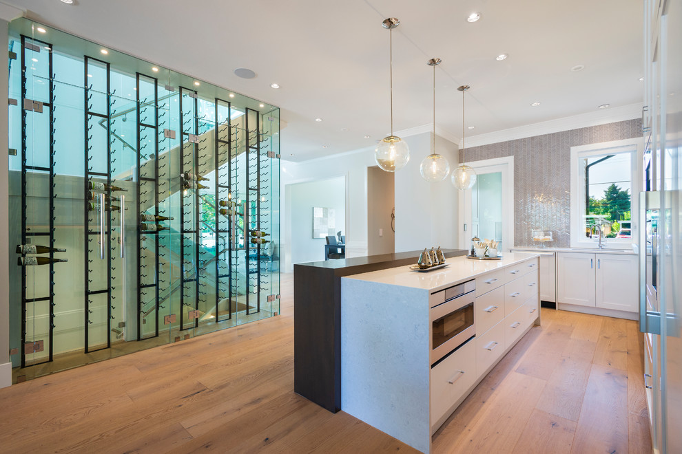 Example of a mid-sized transitional l-shaped light wood floor and beige floor open concept kitchen design in Vancouver with an undermount sink, shaker cabinets, white cabinets, quartz countertops, gray backsplash, mosaic tile backsplash, paneled appliances, an island and gray countertops