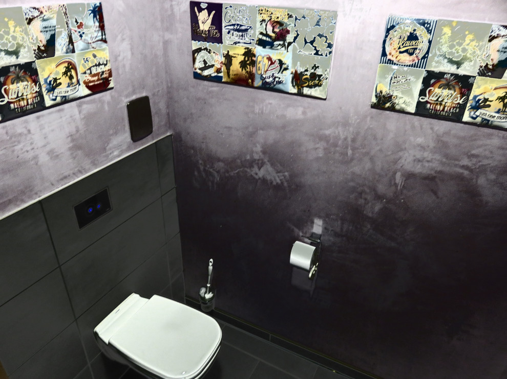 Inspiration för ett mellanstort eklektiskt toalett, med en vägghängd toalettstol, svart kakel, keramikplattor, svarta väggar, klinkergolv i keramik, ett väggmonterat handfat, bänkskiva i glas och svart golv