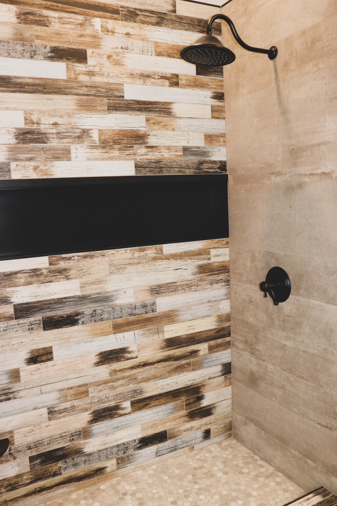 Example of a mid-sized mountain style 3/4 ceramic tile and multicolored tile pebble tile floor and beige floor alcove shower design with beige walls and a hinged shower door