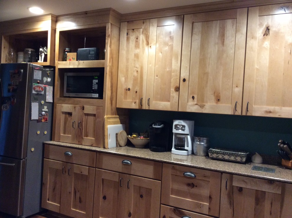 Inspiration for a mid-sized rustic u-shaped medium tone wood floor enclosed kitchen remodel in Houston with no island, recessed-panel cabinets, light wood cabinets, quartzite countertops, ceramic backsplash, black appliances and a farmhouse sink