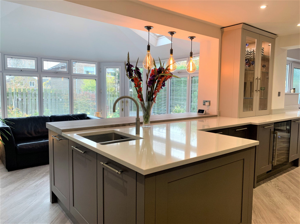 Inspiration for a medium sized classic u-shaped kitchen/diner in Other with a double-bowl sink, shaker cabinets, quartz worktops, glass sheet splashback, stainless steel appliances, vinyl flooring and white worktops.