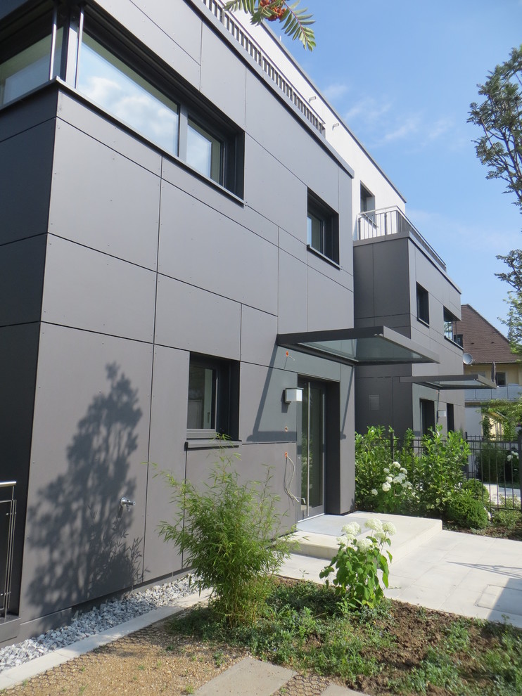 Geräumiges, Dreistöckiges Modernes Haus mit Faserzement-Fassade, grauer Fassadenfarbe und Flachdach in München