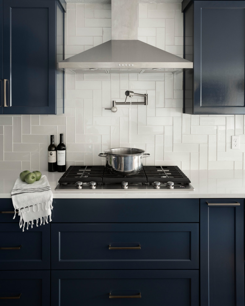 Idéer för ett mellanstort klassiskt vit kök, med en undermonterad diskho, skåp i shakerstil, blå skåp, bänkskiva i kvartsit, vitt stänkskydd, stänkskydd i glaskakel, rostfria vitvaror, laminatgolv, en köksö och brunt golv