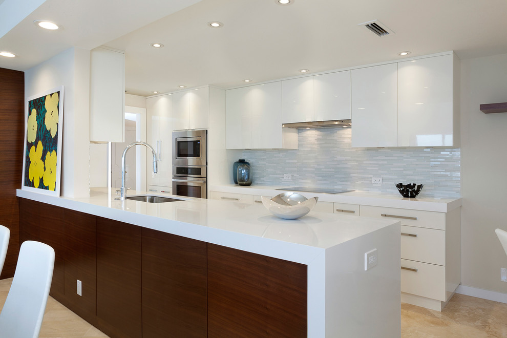 Design ideas for a mid-sized modern kitchen in Miami with flat-panel cabinets, white cabinets, quartz benchtops, white splashback, glass tile splashback, stainless steel appliances, marble floors and with island.