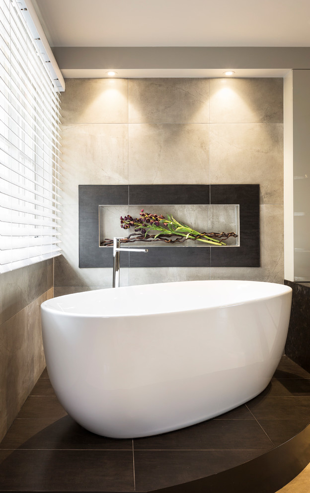 Mid-sized contemporary master bathroom in Melbourne with furniture-like cabinets, beige cabinets, a freestanding tub, a double shower, a one-piece toilet, gray tile, porcelain tile, grey walls, porcelain floors, a console sink, granite benchtops, grey floor and a hinged shower door.