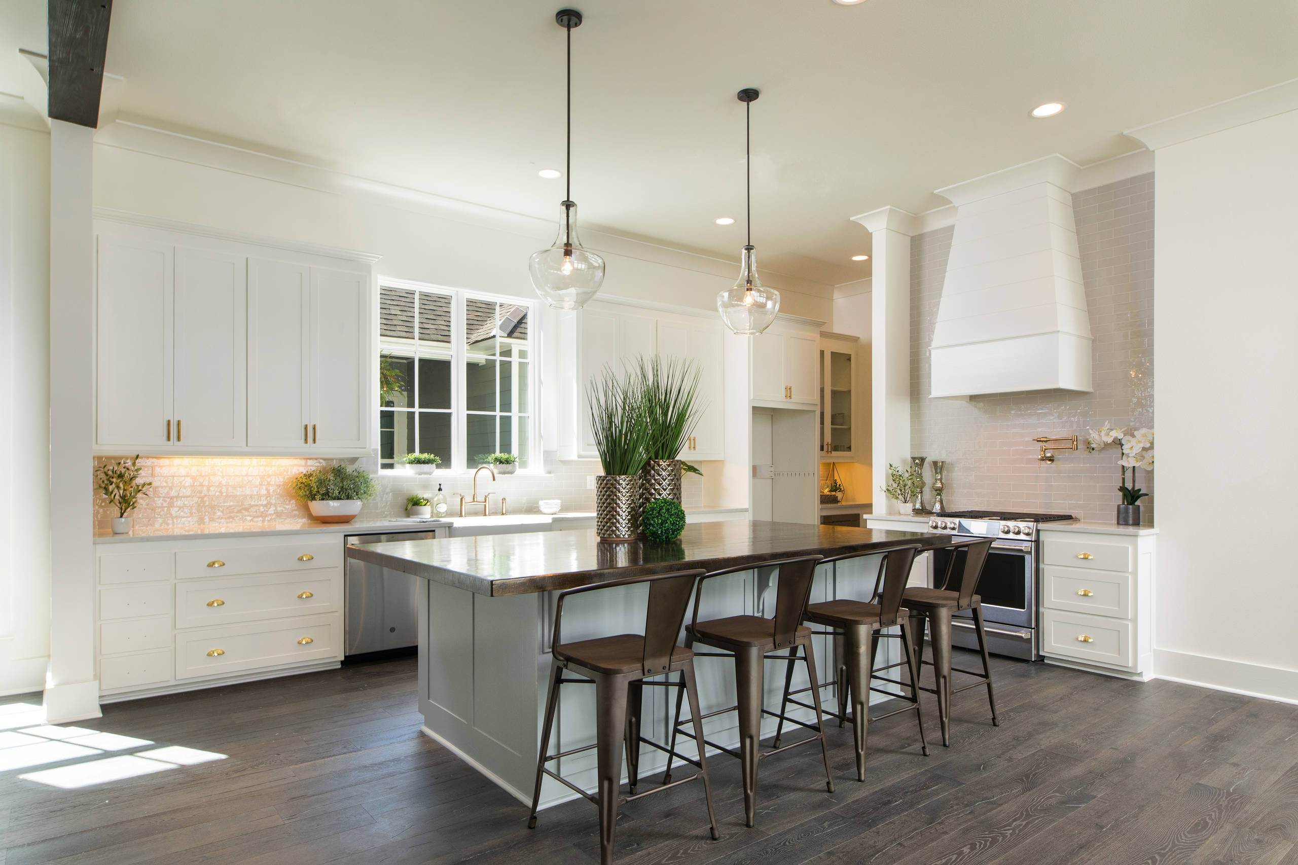 Example of a transitional l-shaped dark wood floor and brown floor eat-in kitchen design in New Orleans with a farmhouse sink, recessed-panel cabinets, white cabinets, gray backsplash, subway tile bac