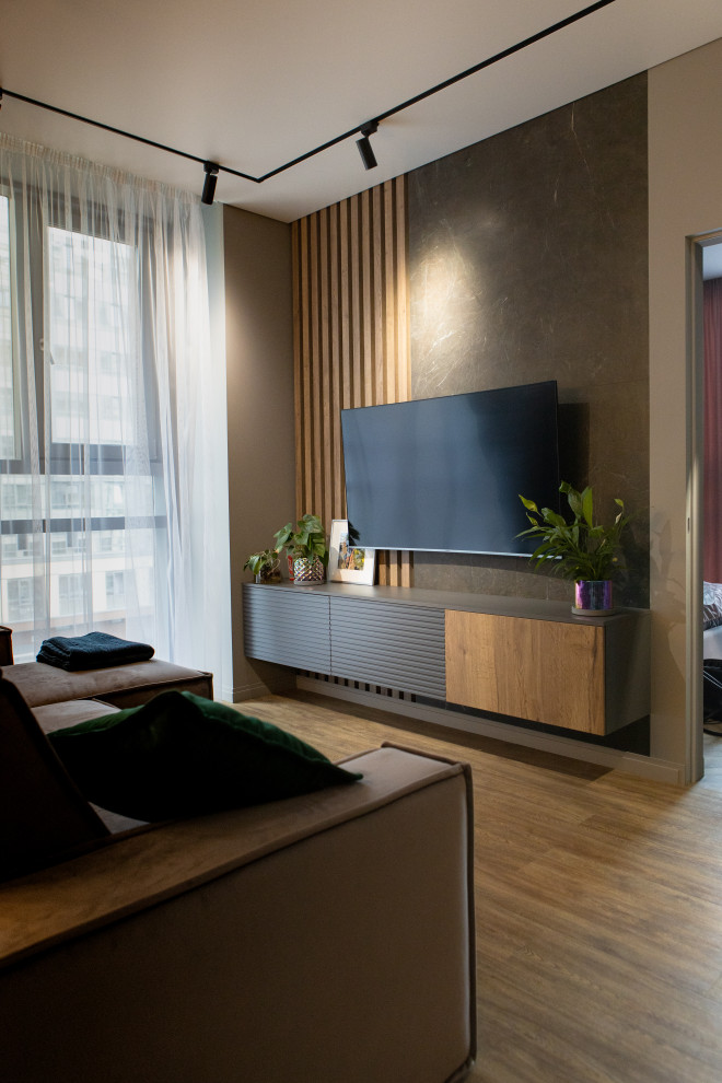 Réalisation d'un petit salon design avec un mur beige, un sol en bois brun, un téléviseur fixé au mur et un sol beige.