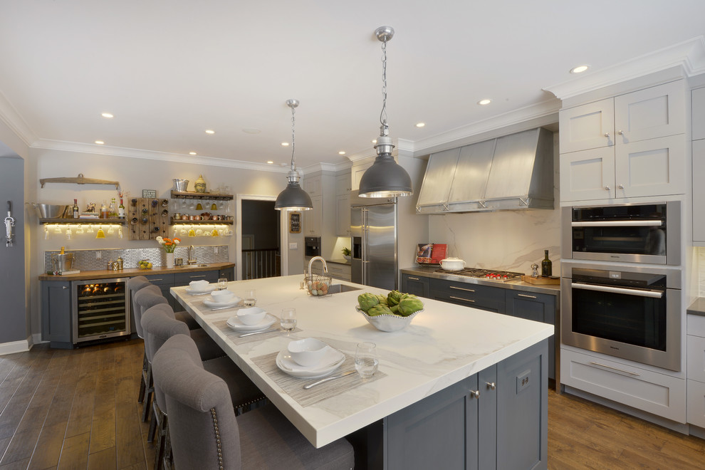 Inspiration for an expansive traditional l-shaped open plan kitchen in New York with an undermount sink, shaker cabinets, grey cabinets, white splashback, stainless steel appliances, medium hardwood floors and with island.