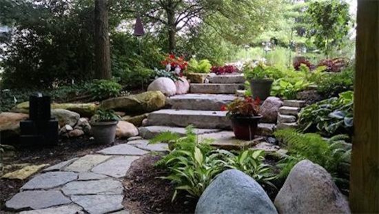 Photo of a mid-sized country backyard shaded garden in Columbus with natural stone pavers.