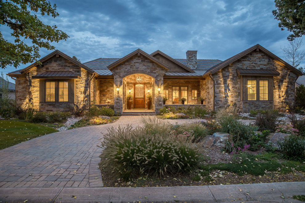 This is an example of a traditional one-storey house exterior in Denver with stone veneer, a gable roof and a tile roof.