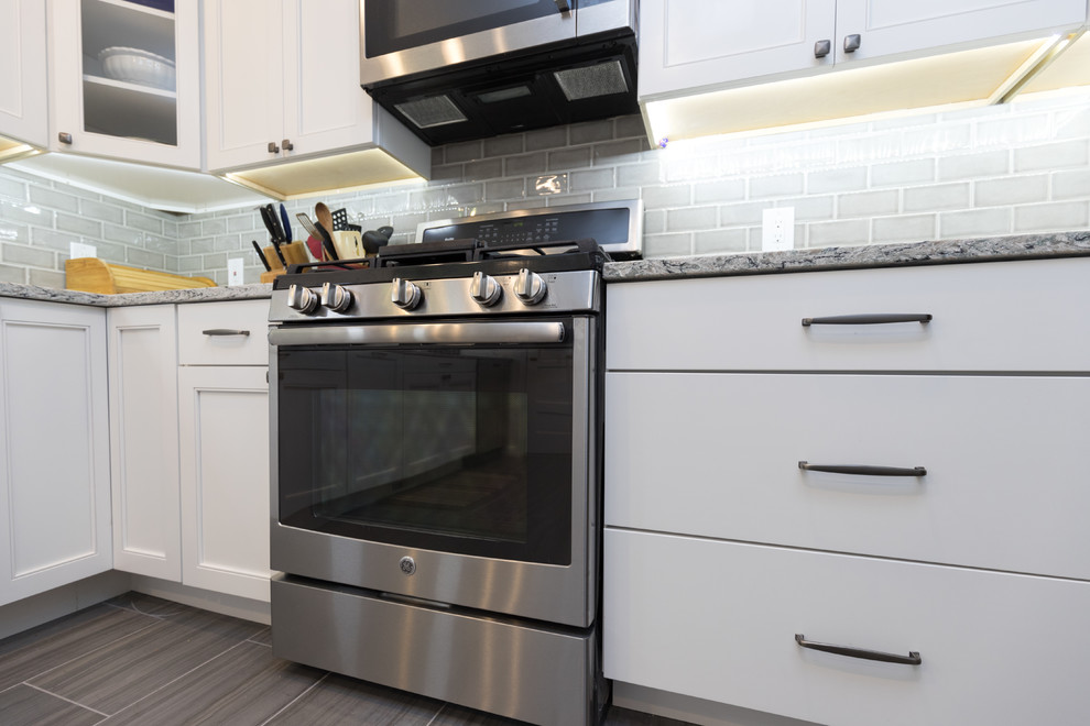 Mid-sized transitional l-shaped porcelain tile and brown floor enclosed kitchen photo in San Diego with an undermount sink, beaded inset cabinets, white cabinets, granite countertops, gray backsplash, ceramic backsplash, stainless steel appliances, no island and gray countertops