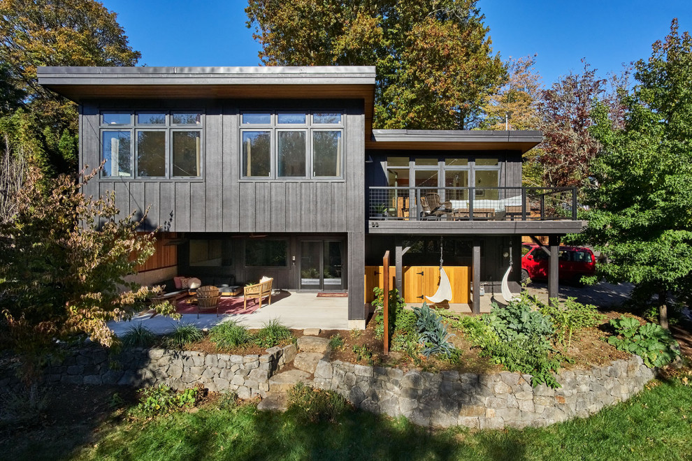 Inspiration for a large 1960s black two-story wood and board and batten house exterior remodel in Portland with a butterfly roof
