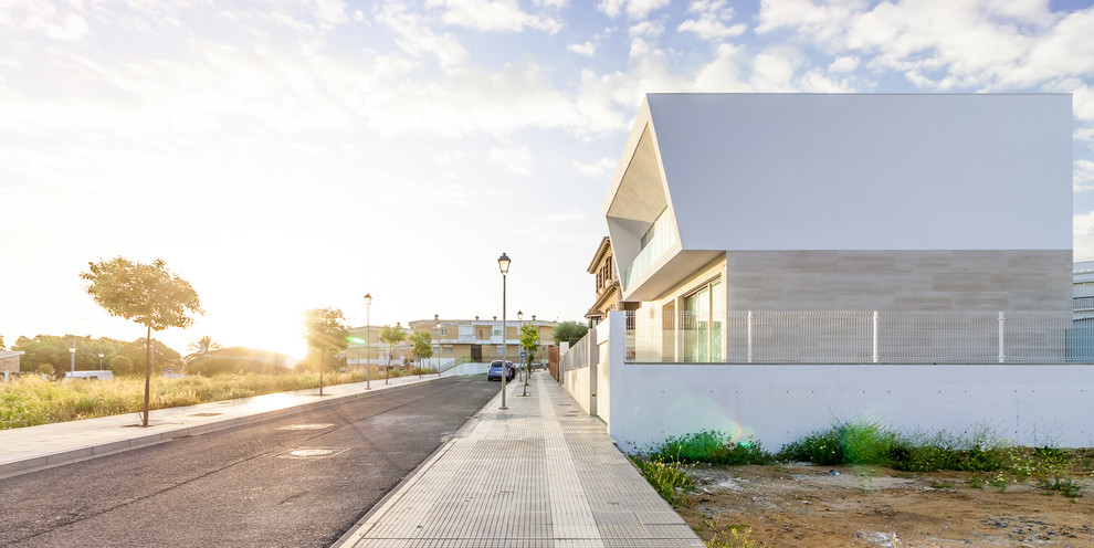 Photo of a large contemporary three-storey white exterior in Seville with mixed siding and a flat roof.