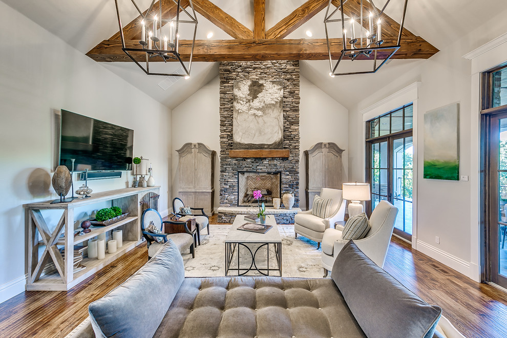 Inspiration for a large transitional formal open concept living room in Oklahoma City with grey walls, medium hardwood floors, a standard fireplace, a stone fireplace surround, a wall-mounted tv and brown floor.