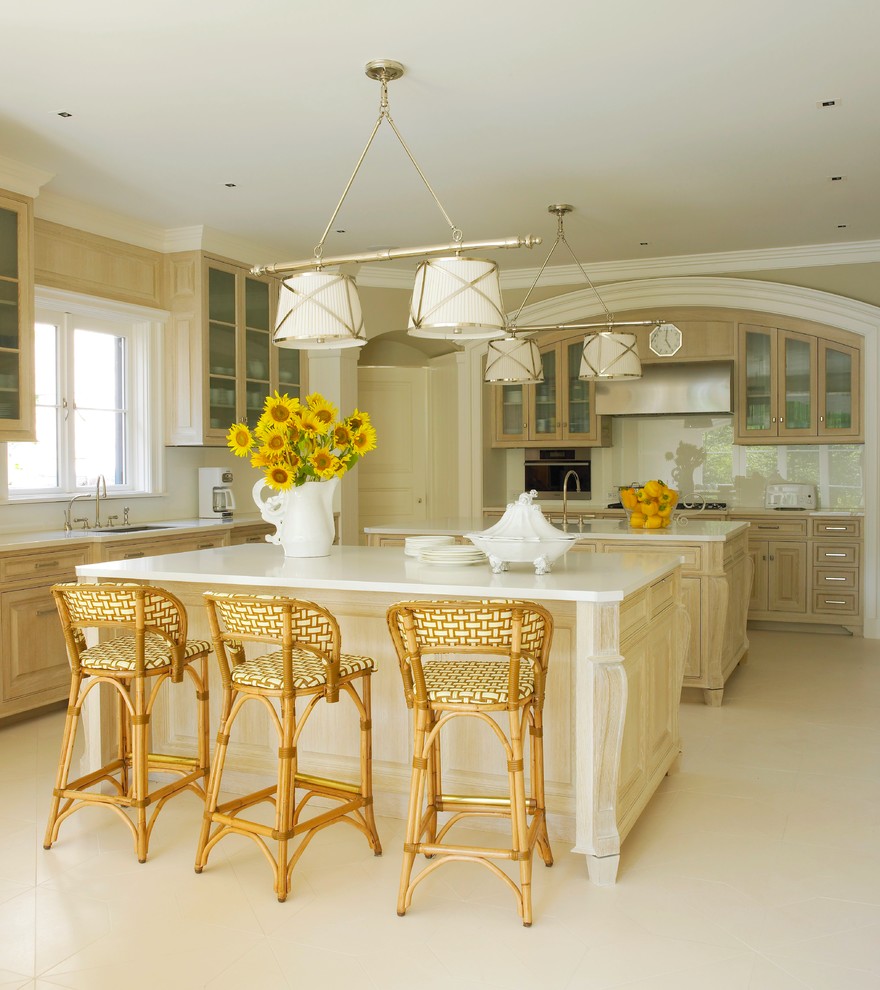 Inspiration for a beach style kitchen in New York with glass-front cabinets, light wood cabinets, beige splashback, glass sheet splashback and multiple islands.