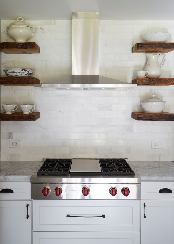 Transitional medium tone wood floor kitchen photo in Chicago with a farmhouse sink, white cabinets, quartzite countertops, white backsplash, stone tile backsplash, stainless steel appliances and an island