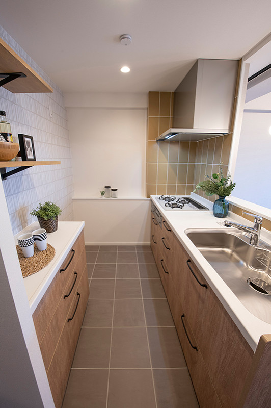 Minimalistisk inredning av ett mellanstort vit linjärt vitt kök med öppen planlösning, med en integrerad diskho, släta luckor, skåp i mellenmörkt trä, bänkskiva i koppar, gult stänkskydd, vita vitvaror, klinkergolv i porslin och grått golv