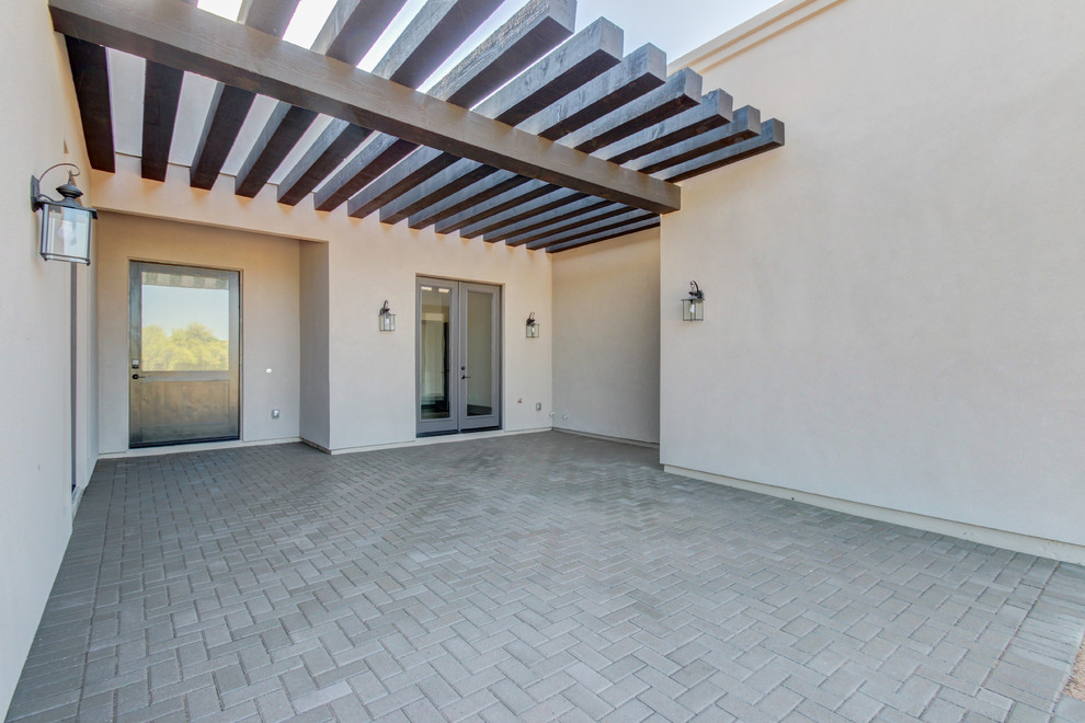 Example of a mid-sized transitional backyard concrete paver patio design in Phoenix with a pergola