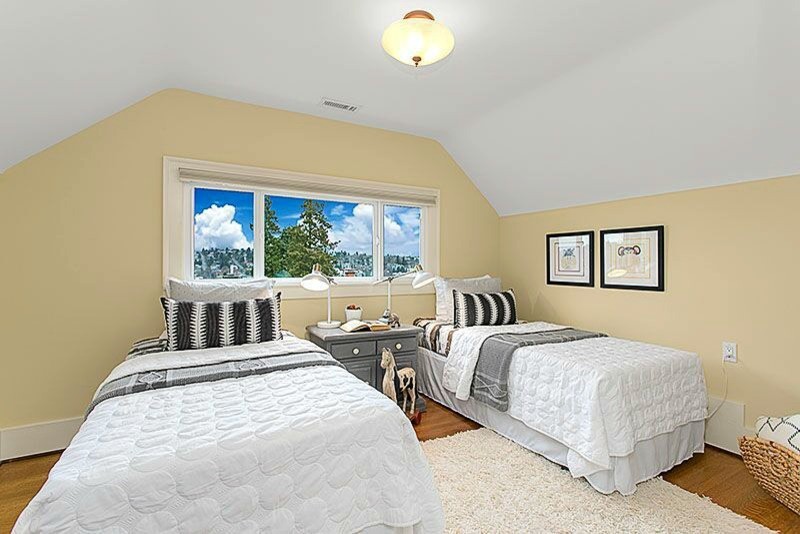 This is an example of a small arts and crafts gender-neutral kids' bedroom for kids 4-10 years old in Seattle with yellow walls and light hardwood floors.
