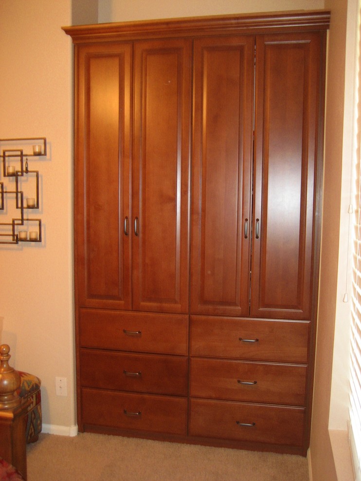 Photo of a small traditional gender-neutral built-in wardrobe in Phoenix with raised-panel cabinets and medium wood cabinets.