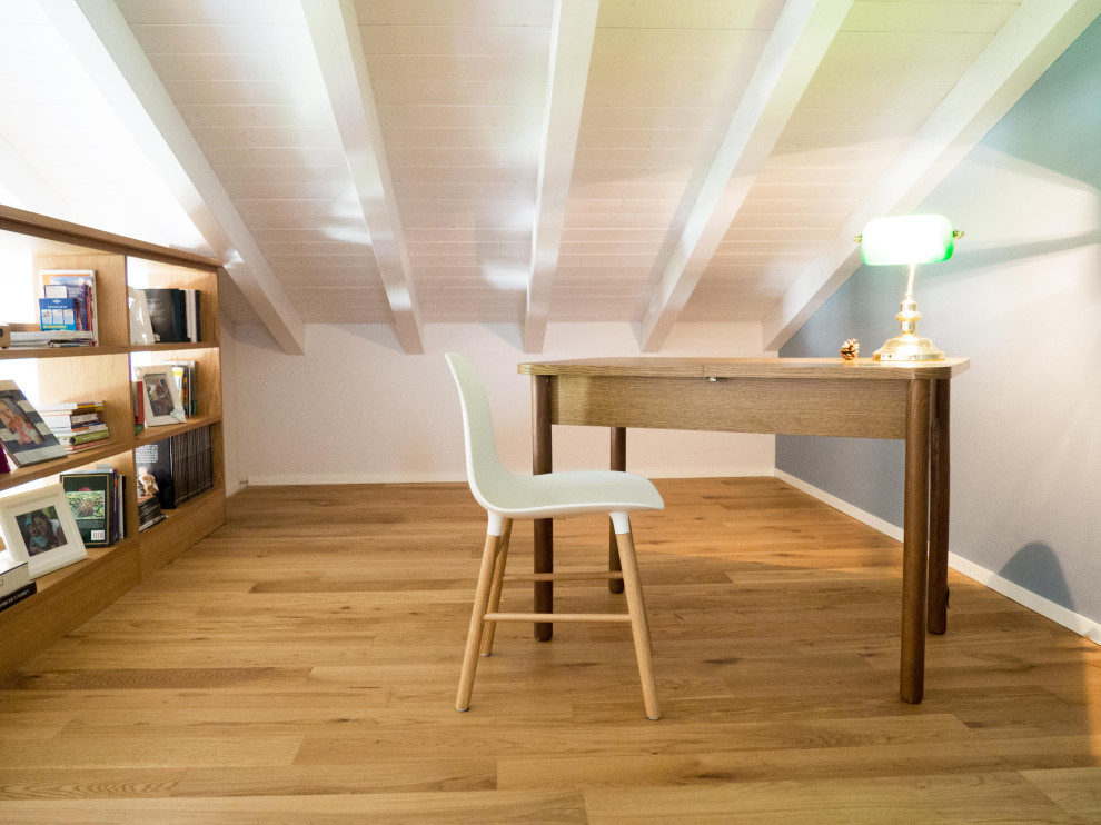 Bild på ett litet minimalistiskt arbetsrum, med ett bibliotek, blå väggar och mellanmörkt trägolv