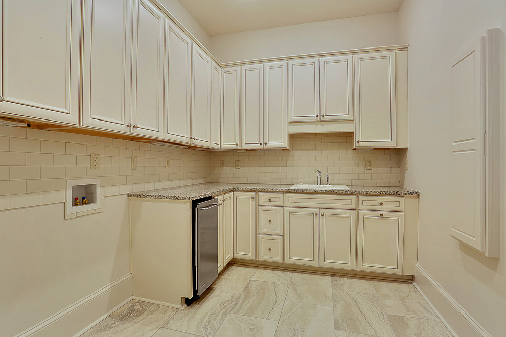 Photo of a traditional l-shaped dedicated laundry room in New Orleans with a drop-in sink, recessed-panel cabinets, white cabinets, granite benchtops, white walls, ceramic floors and a side-by-side washer and dryer.