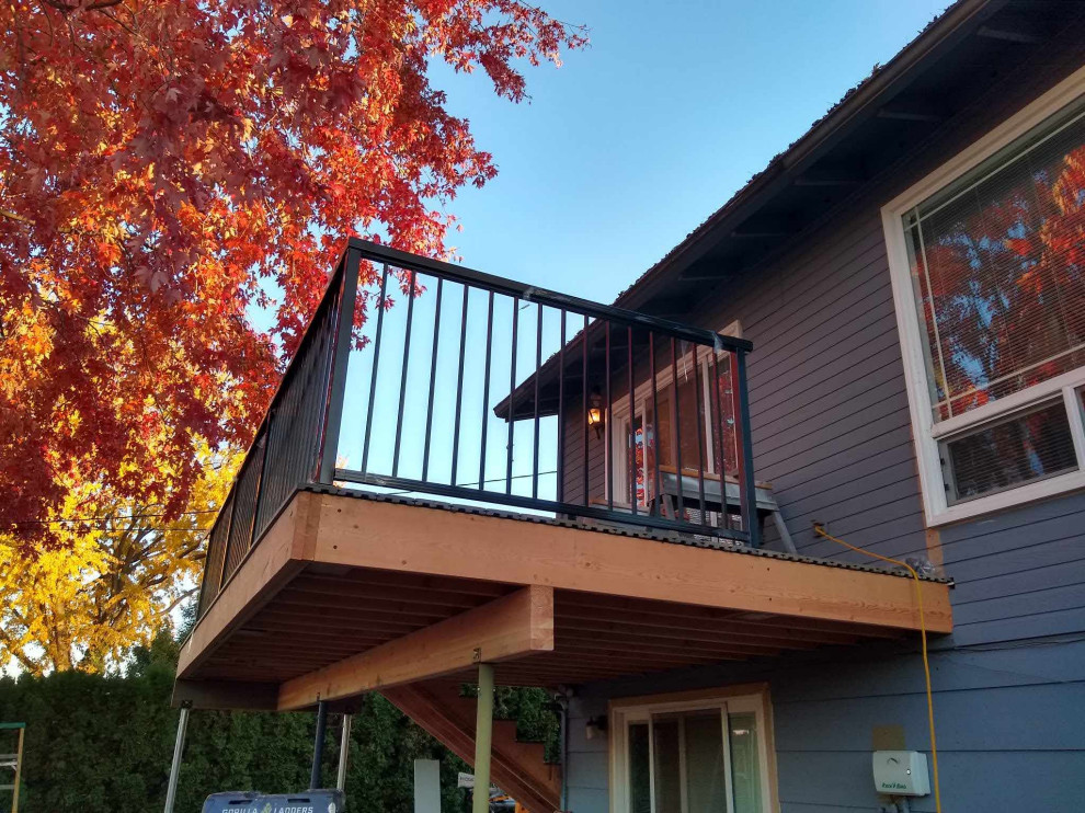 Example of a mid-sized minimalist backyard second story metal railing deck design in Seattle with an awning