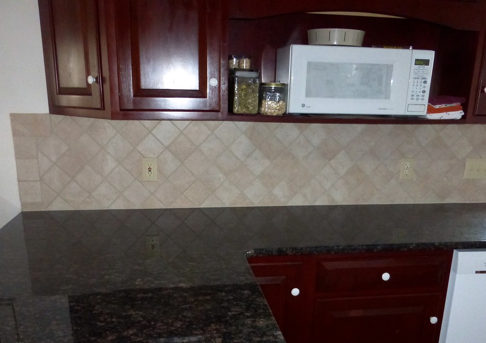 Home design - mid-sized traditional l-shaped home design idea with raised-panel cabinets, dark wood cabinets, granite countertops, beige backsplash, porcelain backsplash, white appliances and a peninsula