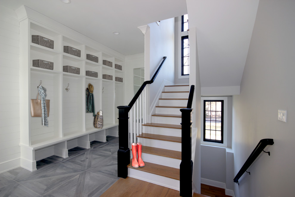 Photo of a mid-sized transitional mudroom in New York with white walls, porcelain floors, a single front door, a black front door and grey floor.