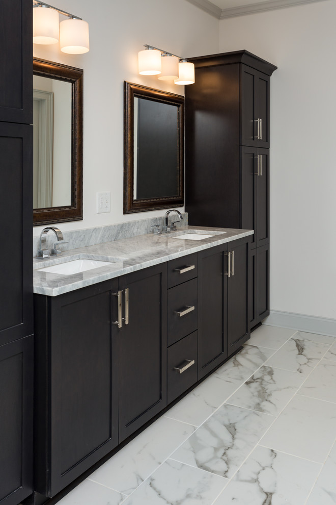 This is an example of a mid-sized transitional master bathroom in Atlanta with shaker cabinets, dark wood cabinets, a freestanding tub, a double shower, a one-piece toilet, gray tile, porcelain tile, white walls, marble floors, an undermount sink and granite benchtops.