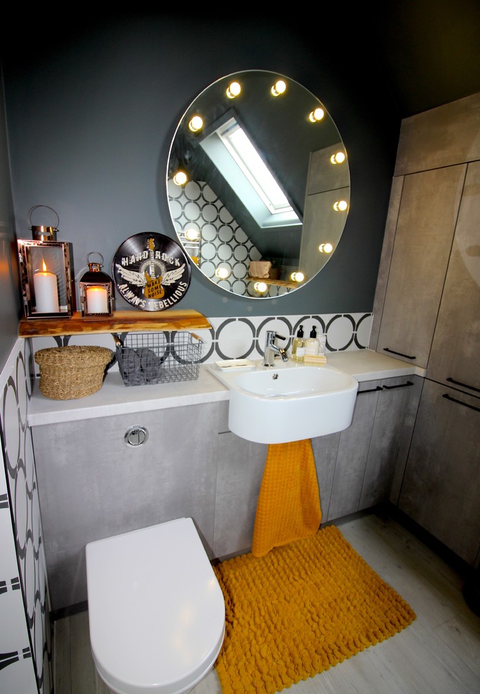 Inspiration for a small industrial bathroom in Sussex with flat-panel cabinets, grey cabinets, grey walls, white benchtops, a wall-mount toilet, black and white tile, multi-coloured tile, a wall-mount sink and beige floor.