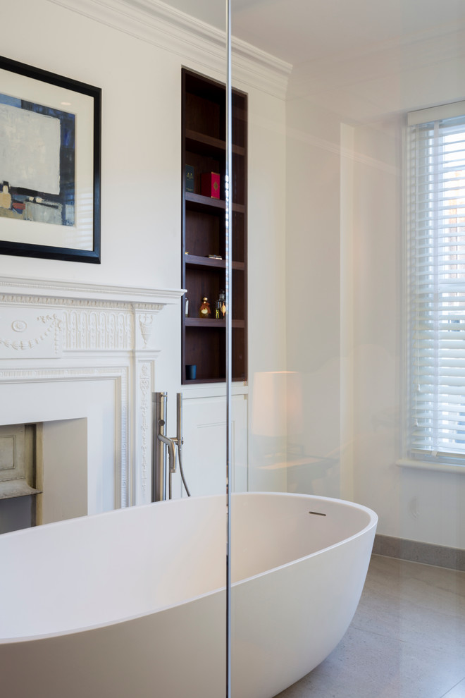 Photo of a mid-sized contemporary master bathroom in London with dark wood cabinets, a freestanding tub, an open shower, a wall-mount toilet, beige tile, stone slab, white walls, marble floors and marble benchtops.