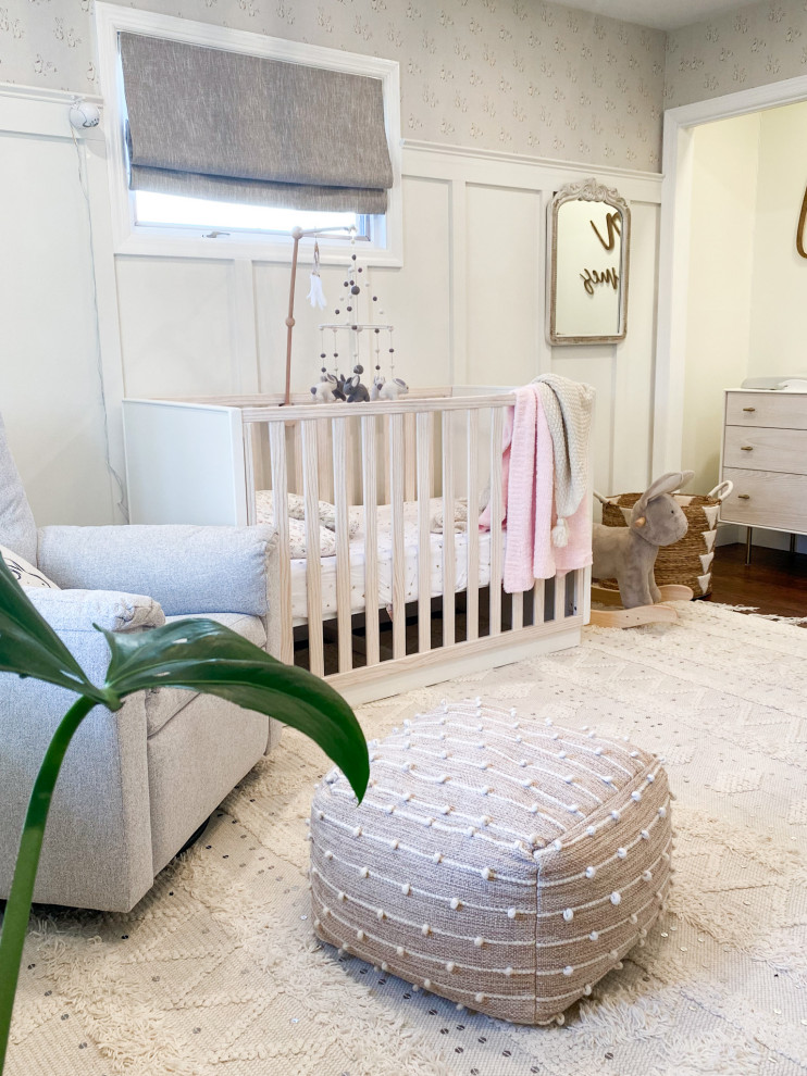 Modelo de habitación de bebé niña romántica de tamaño medio con paredes blancas, suelo de madera en tonos medios, suelo marrón y papel pintado