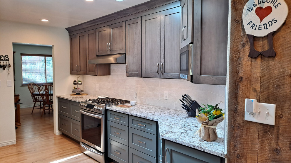 Example of a mid-sized transitional galley light wood floor kitchen design in Denver with shaker cabinets, porcelain backsplash and stainless steel appliances