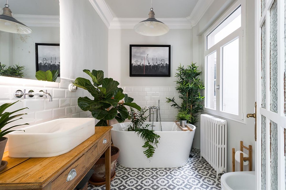 This is an example of a mid-sized transitional master bathroom in Other with medium wood cabinets, a freestanding tub, white walls, ceramic floors, a vessel sink, wood benchtops, multi-coloured floor, white tile, subway tile and flat-panel cabinets.