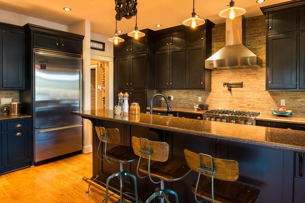 Mid-sized transitional l-shaped medium tone wood floor open concept kitchen photo in DC Metro with an undermount sink, shaker cabinets, black cabinets, quartz countertops, brown backsplash, stainless steel appliances, an island and stone tile backsplash