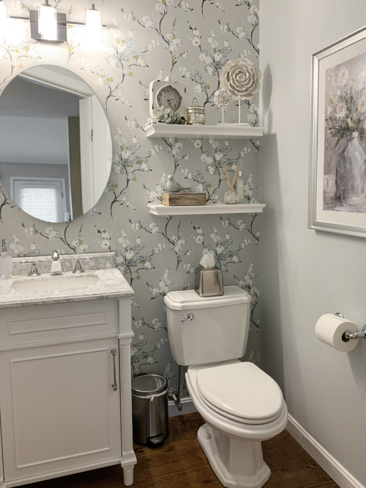 Inspiration for a medium sized traditional cloakroom with white cabinets, a one-piece toilet, blue walls, medium hardwood flooring, marble worktops and wallpapered walls.