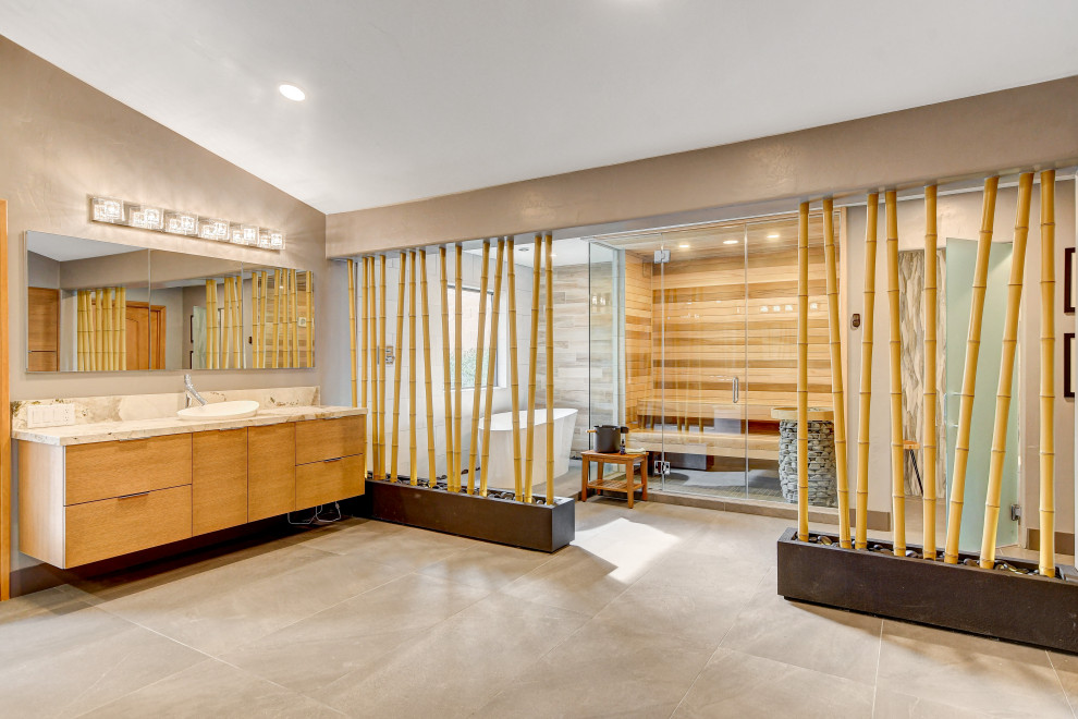 Imagen de cuarto de baño único y flotante tropical con puertas de armario de madera clara, bañera exenta y encimera de mármol