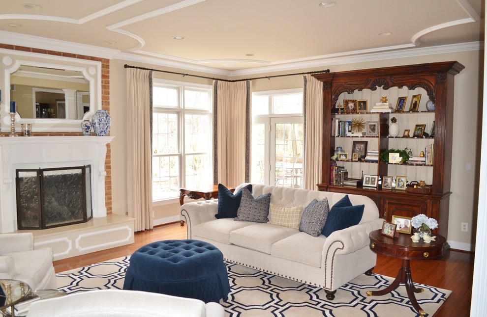 This is an example of a traditional living room in Baltimore with a library, beige walls, medium hardwood floors, a standard fireplace, a brick fireplace surround and a concealed tv.