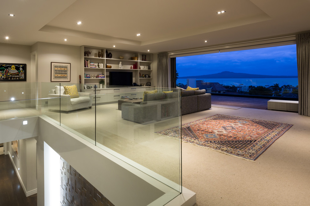 This is an example of a large contemporary open concept living room in Auckland with grey walls, carpet, no fireplace, a built-in media wall and grey floor.