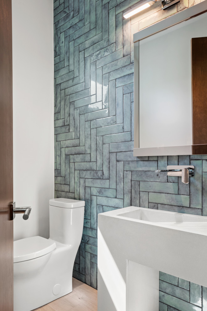 Inspiration for a mid-sized powder room in Tampa with white cabinets, a one-piece toilet, blue tile, glass tile, white walls, light hardwood floors, a vessel sink, concrete benchtops, brown floor, white benchtops and a freestanding vanity.