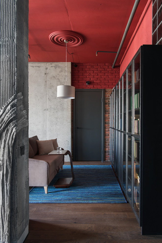 Mittelgroßes Industrial Arbeitszimmer ohne Kamin mit Arbeitsplatz, roter Wandfarbe, dunklem Holzboden, freistehendem Schreibtisch, braunem Boden und Ziegelwänden in Moskau