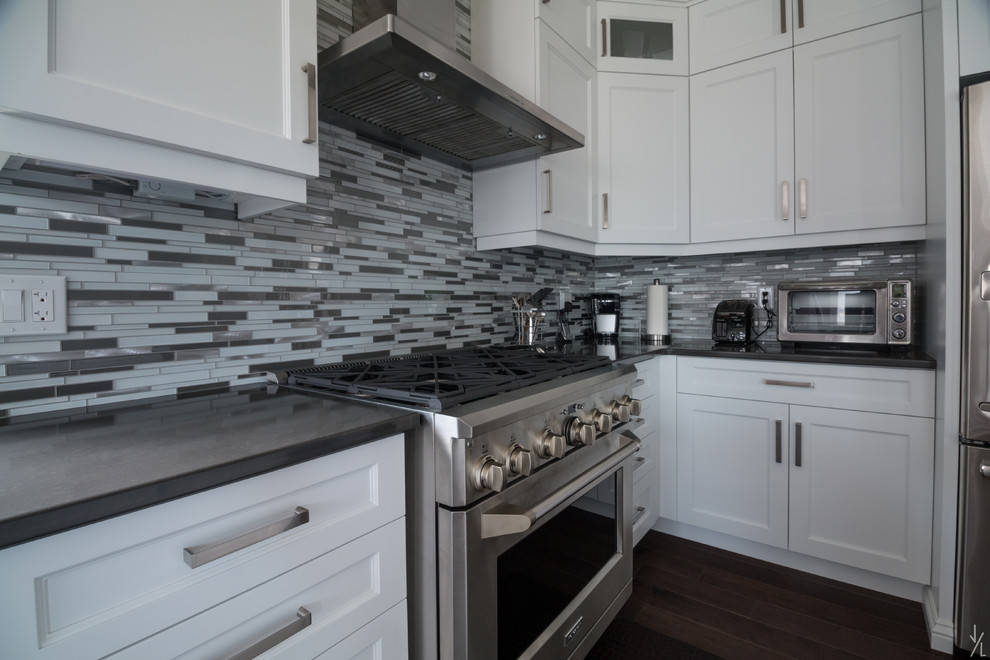 Photo of a large contemporary l-shaped eat-in kitchen in Toronto with an undermount sink, recessed-panel cabinets, white cabinets, quartzite benchtops, multi-coloured splashback, glass tile splashback, stainless steel appliances, dark hardwood floors and with island.
