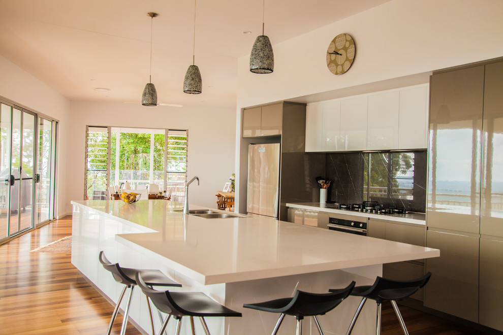 Inspiration for a large modern galley eat-in kitchen in Sunshine Coast with a double-bowl sink, white cabinets, quartz benchtops, grey splashback, marble splashback, stainless steel appliances, with island and white benchtop.