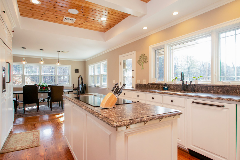 Eat-in kitchen - large modern galley light wood floor and brown floor eat-in kitchen idea with a single-bowl sink, raised-panel cabinets, white cabinets, quartzite countertops, brown backsplash, paneled appliances, an island and brown countertops