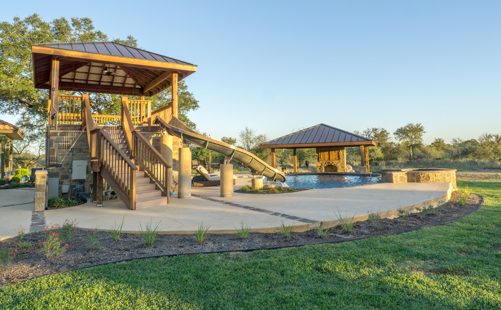 Pool fountain - large rustic backyard stone and custom-shaped pool fountain idea in Austin