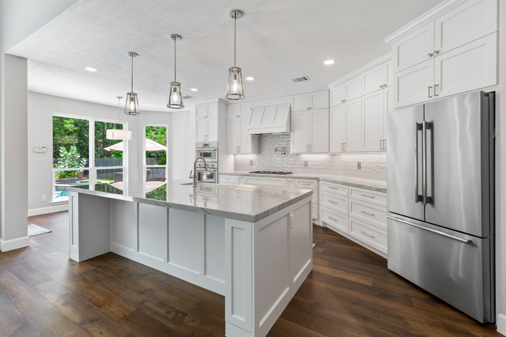 Mid-sized transitional single-wall dark wood floor and brown floor eat-in kitchen photo in Houston with a farmhouse sink, beaded inset cabinets, white cabinets, quartzite countertops, gray backsplash, ceramic backsplash, stainless steel appliances, an island and gray countertops