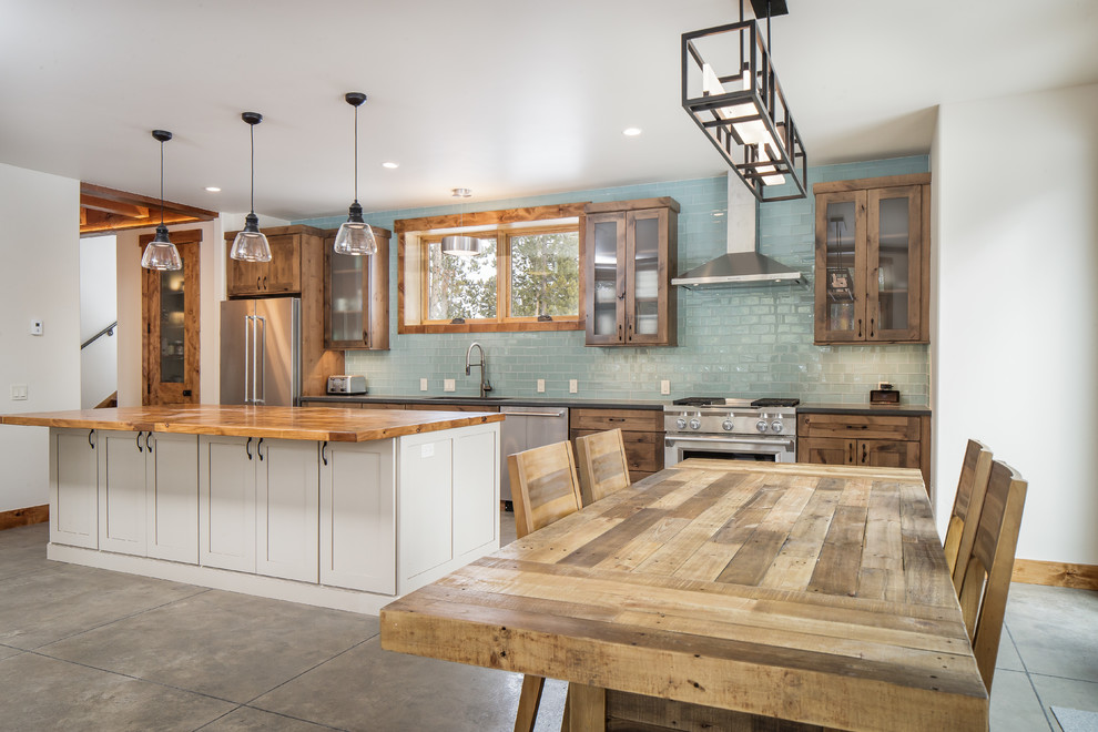 Inspiration for a mid-sized rustic single-wall eat-in kitchen remodel in Denver with an undermount sink, shaker cabinets, distressed cabinets, quartz countertops, blue backsplash, glass tile backsplash, stainless steel appliances, an island and gray countertops