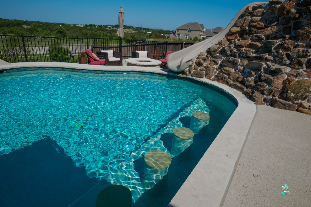 Imagen de piscina con tobogán natural de estilo americano extra grande a medida en patio lateral con entablado