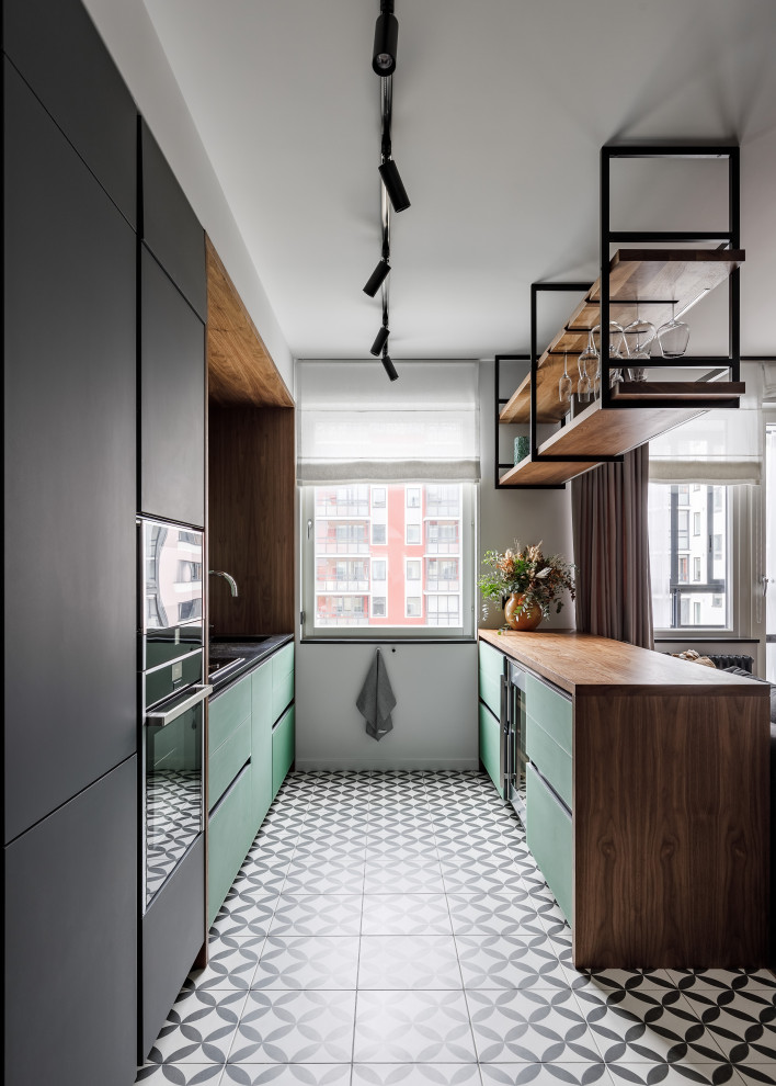Bild på ett mellanstort funkis svart svart kök, med släta luckor, gröna skåp, bänkskiva i koppar, en köksö, en enkel diskho, grönt stänkskydd, svarta vitvaror, klinkergolv i keramik och grått golv